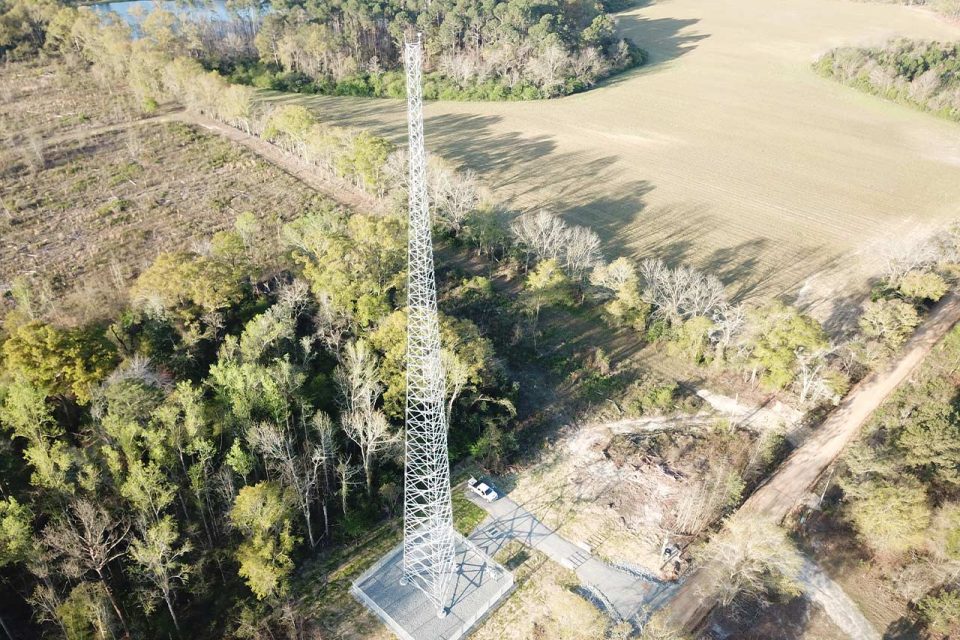 Tall telecommunication tower beside a field